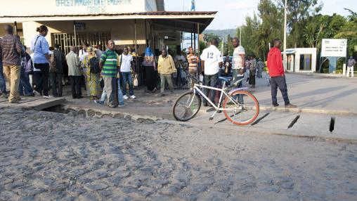 Des hommes et des femmes se tiennent devant un bureau d'immigration à la frontière entre la République démocratique du Congo et le Rwanda