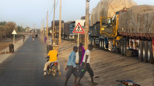 Pedestrians and covered trucks at the border between Mali and Senegal