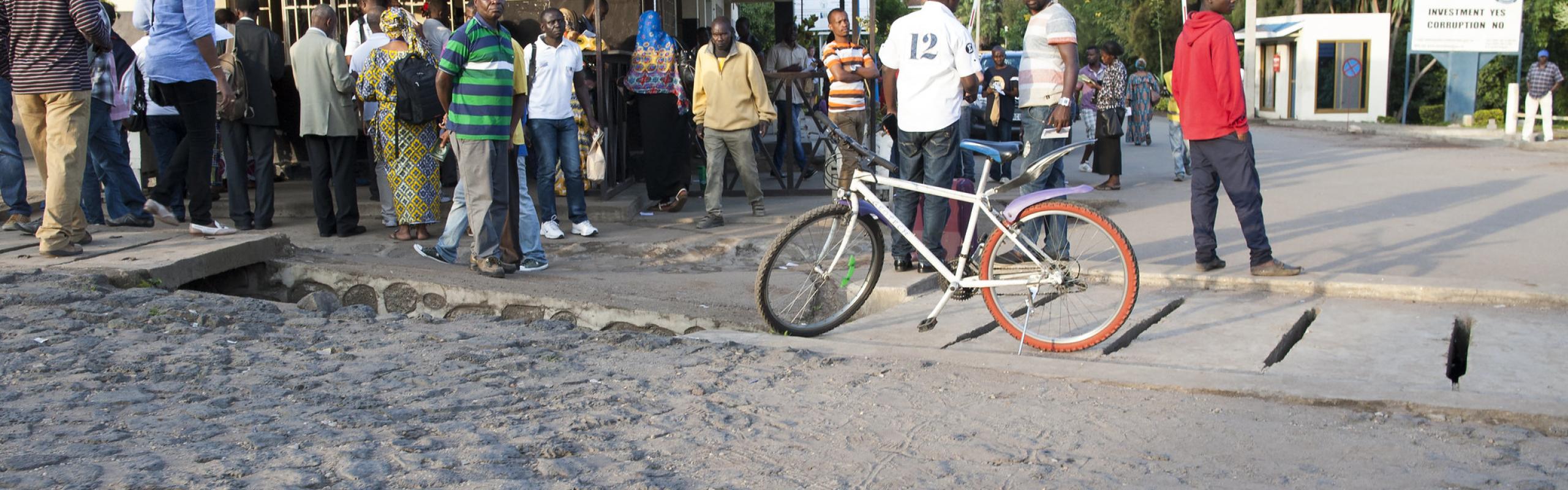 Des hommes et des femmes se tiennent devant un bureau d'immigration à la frontière entre la République démocratique du Congo et le Rwanda