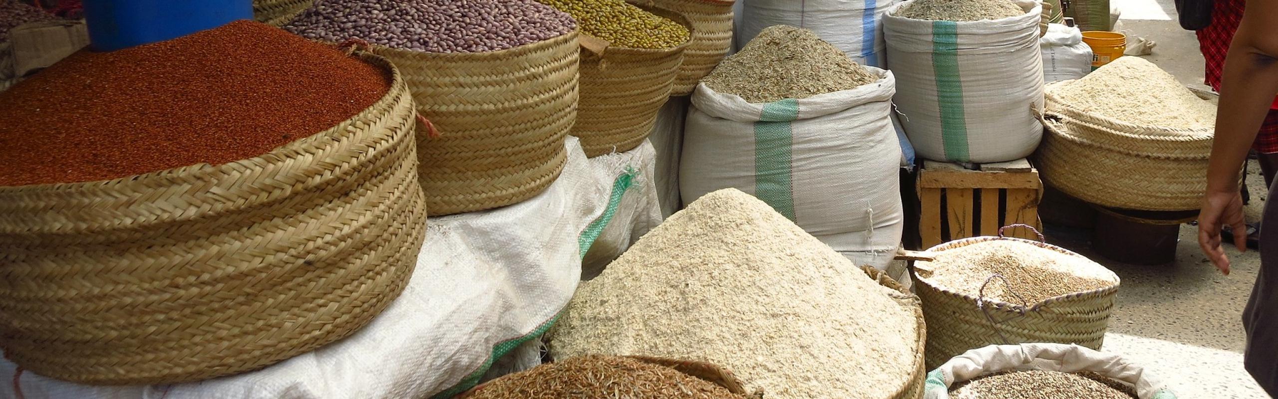 Des tas de céréales, de légumineuses et d'épices dans des sacs en tissu sur un marché en plein air en Afrique