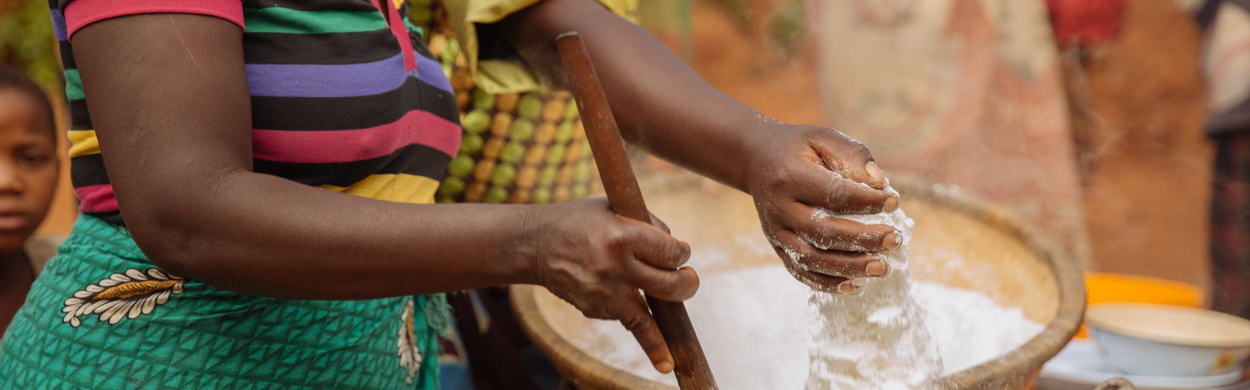  Des femmes préparant un repas commun tamisent à la main de la farine de maïs dans une marmite dans un village du Malawi. La hausse des prix mondiaux du maïs pourrait avoir un impact sur la population pauvre du pays.