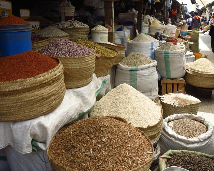 Des tas de céréales, de légumineuses et d'épices dans des sacs en tissu sur un marché en plein air en Afrique