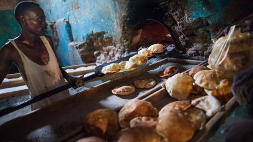 A baker takes bread out of the oven in his bakery in El Fasher, Sudan. Wheat and bread prices in Sudan are spiking, driven by domestic problems and the market disruptions of the Russia-Ukraine war.