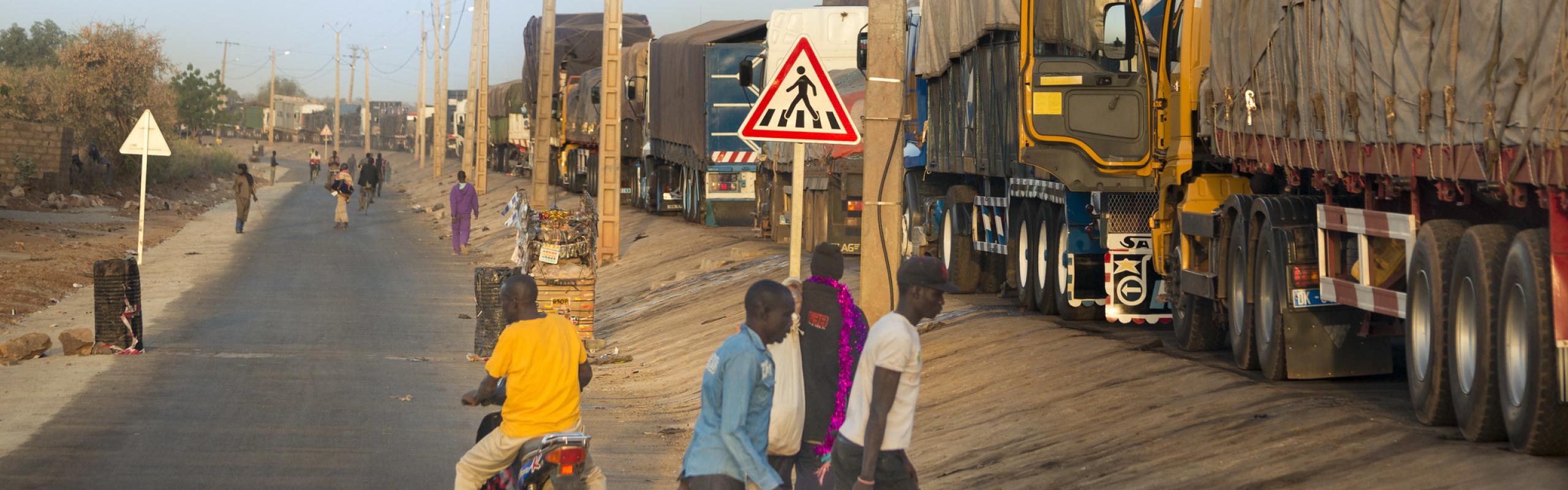 Pedestrians and covered trucks at the border between Mali and Senegal